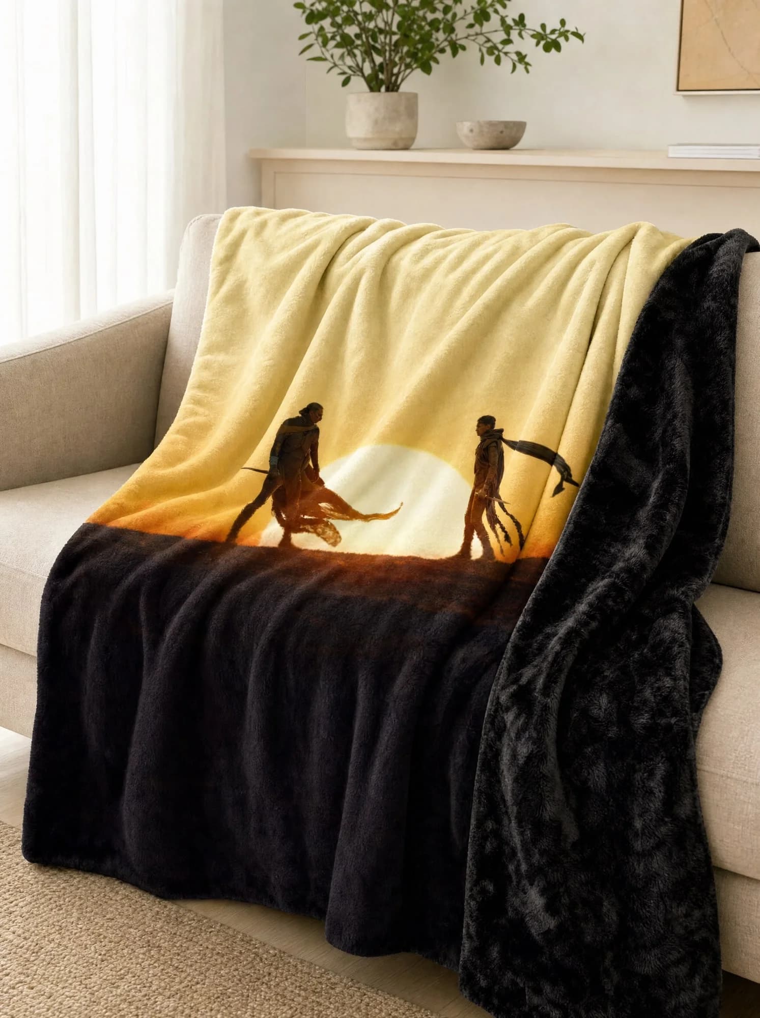 A custom printed minky blanket draped over a sofa: two figures and a desert sunset printed on the front, black plush on the back.